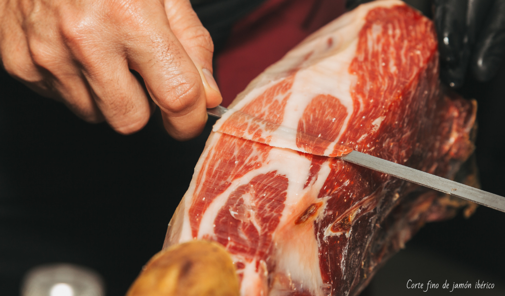 Manos de un profesional cortando jamón muy fino